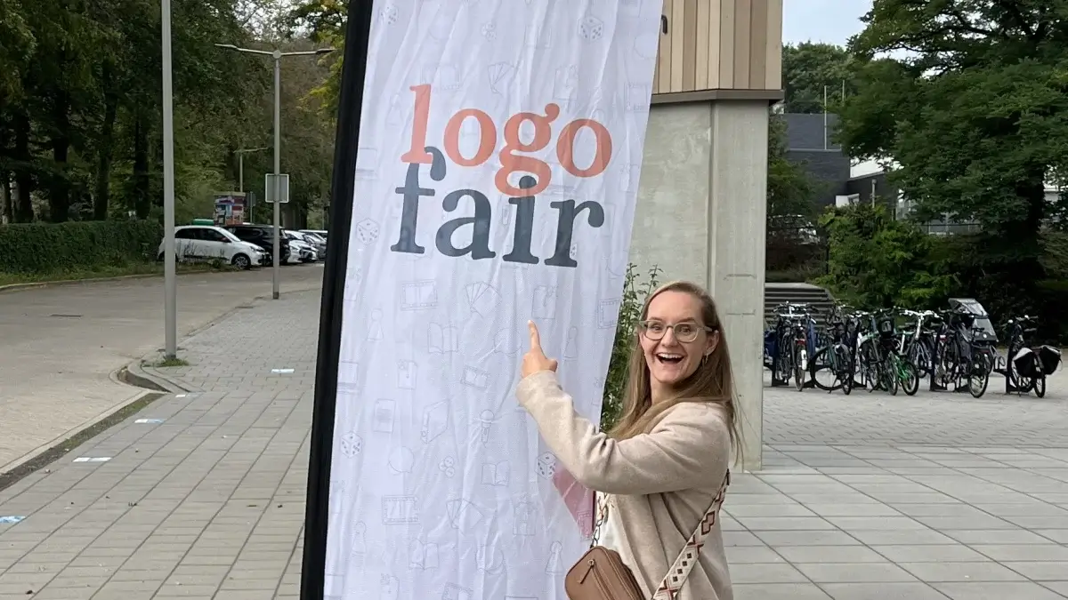 Kim De Raeve wijst naar de vlag van Logo Fair 2026 in Arnhem