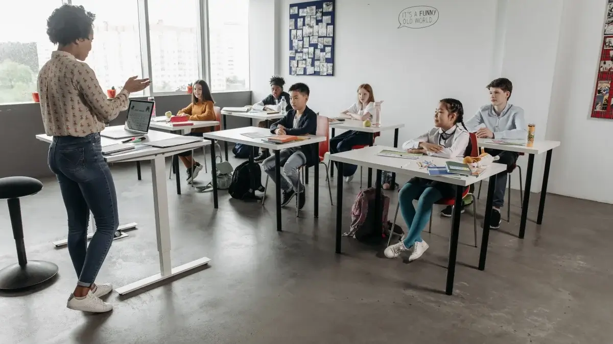 Leerkracht spreekt staand voor haar klas, de stembelasting achter stemklachten bij leerkrachten